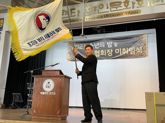 지난 12일 오후 노크로스에 있는 애틀랜타 한인회관에서 이강하 신임 회장이 협회기를 받은 뒤 흔들고 있다. 