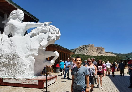 수(Sioux)족의 한 갈래인 라코타 인디언 추장이었던 크레이지 호스(Crazy Horse) 조각상 앞에서 관광객들이 사진을 찍고 있다. 사우스다코타 주 블랙힐스 산지에 있는 이 조각상은 70년 넘게 공사 중이며 현재 얼굴 부분만 완성되어 있다. 크레이지 호스의 원래 뜻은 ‘길들이지 않은 말’이란 뜻이다. 그는 리틀빅혼 (Little Big Horn) 전투에서 조지 커스터 장군이 이끄는 미국 기병대를 전멸시킨 아메리카 인디언들의 전설적 영웅이 됐다. 사진 앞쪽 흰색 조형물은 완공 후의 모습이다. [사진=이종호] 