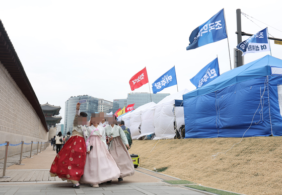 12일 외국인 관광객들이 서울 종로구 광화문 인근에 설치된 탄핵 촉구 장외 농성 텐트 인근을 지나치고 있다. 연합뉴스